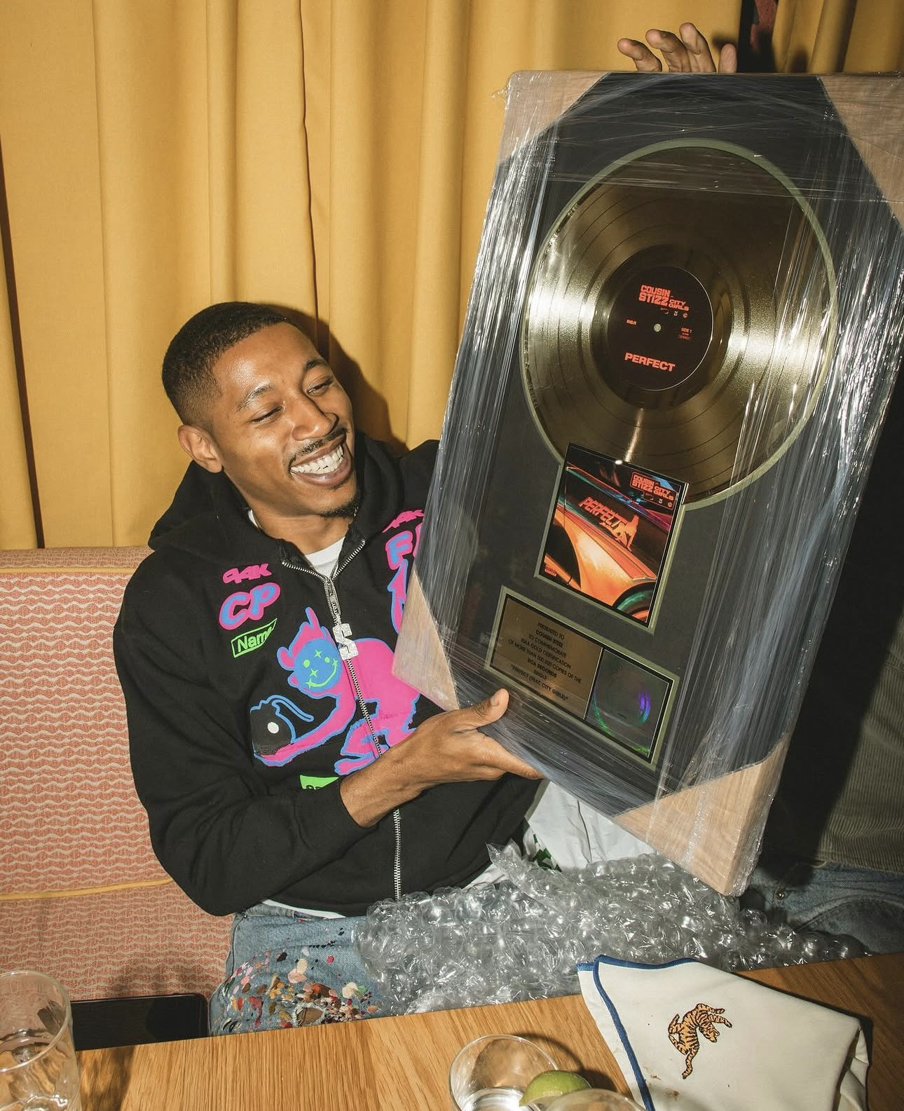 Placa enmarcada de la RIAA con un disco de oro y la inscripción del certificado de Disco de Oro por «Perfect (feat. City Girls)», sostenida por Cousin Stizz