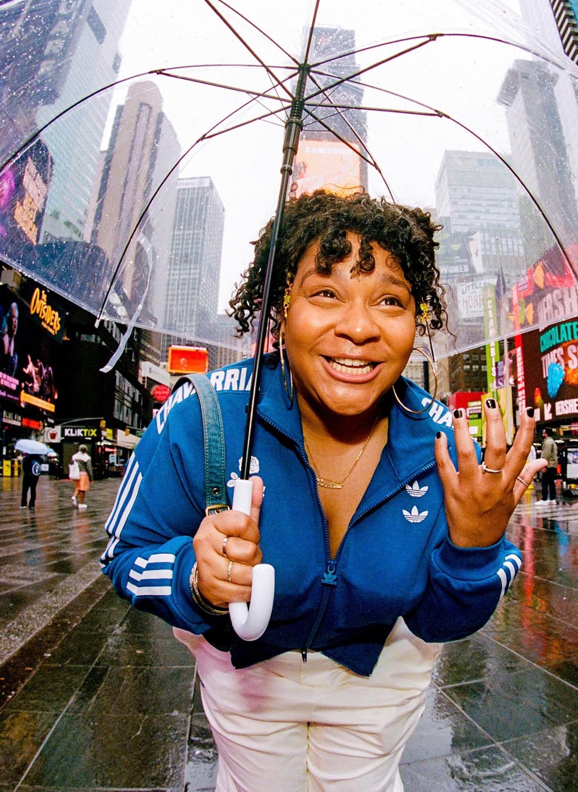Carolina Montesquieu sonríe bajo un paraguas transparente en Times Square, Nueva York, en un día de lluvia.