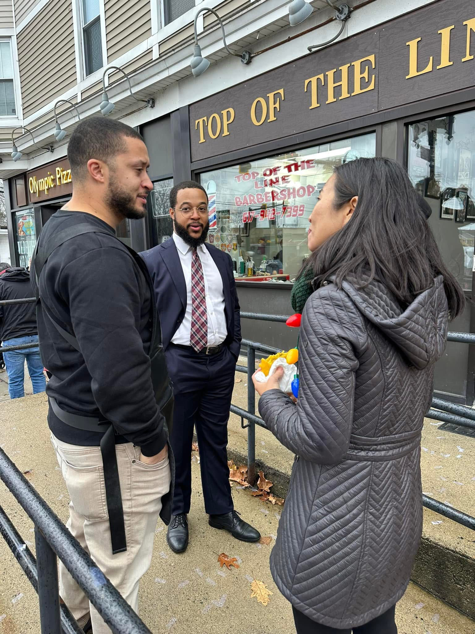 Damian King conversando con la alcaldesa de Boston, Michelle Wu, frente a Top Of The Line Barbershop
