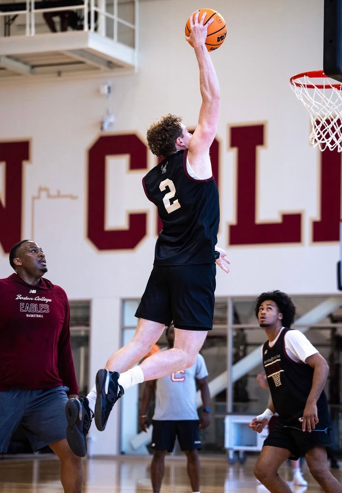 Colby Duggan atrapando un rebote en un entrenamiento de Boston College, señalética de Boston College Eagles detrás