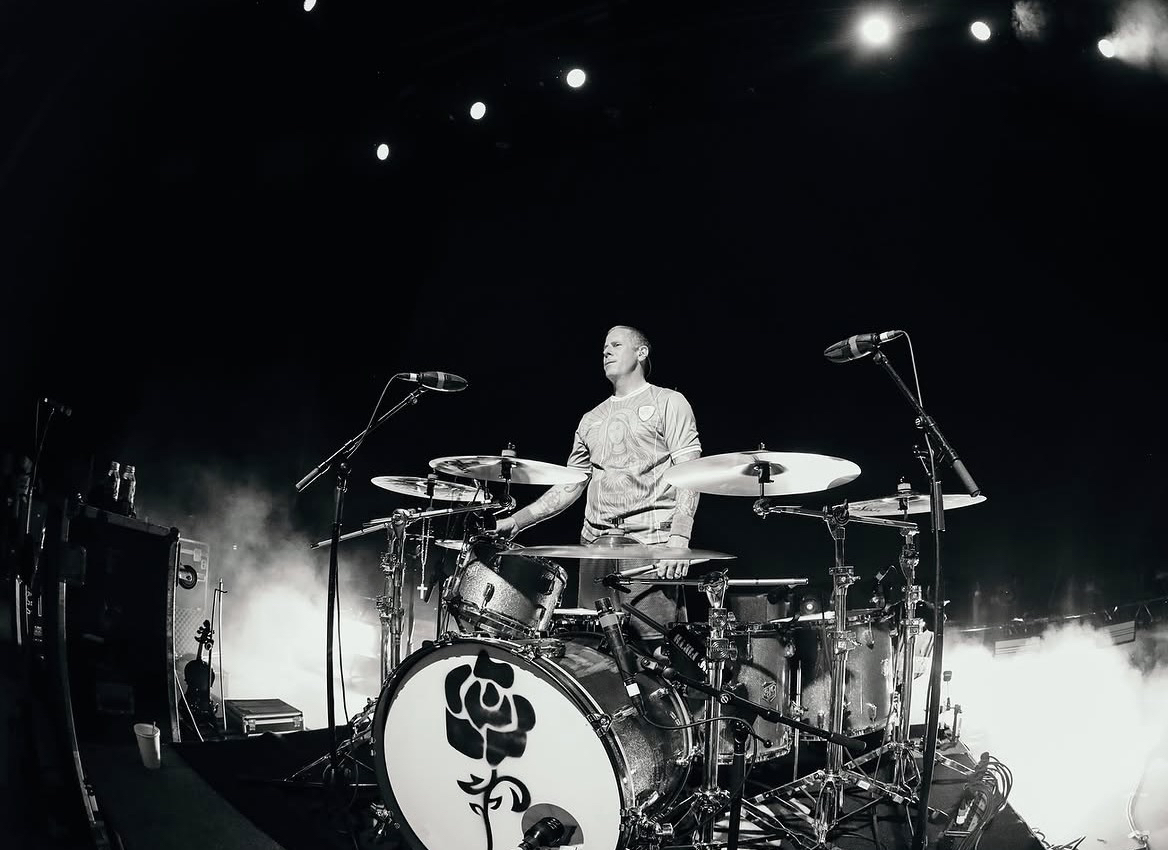 El baterista de Dropkick Murphys detrás de un set con un emblema de rosa