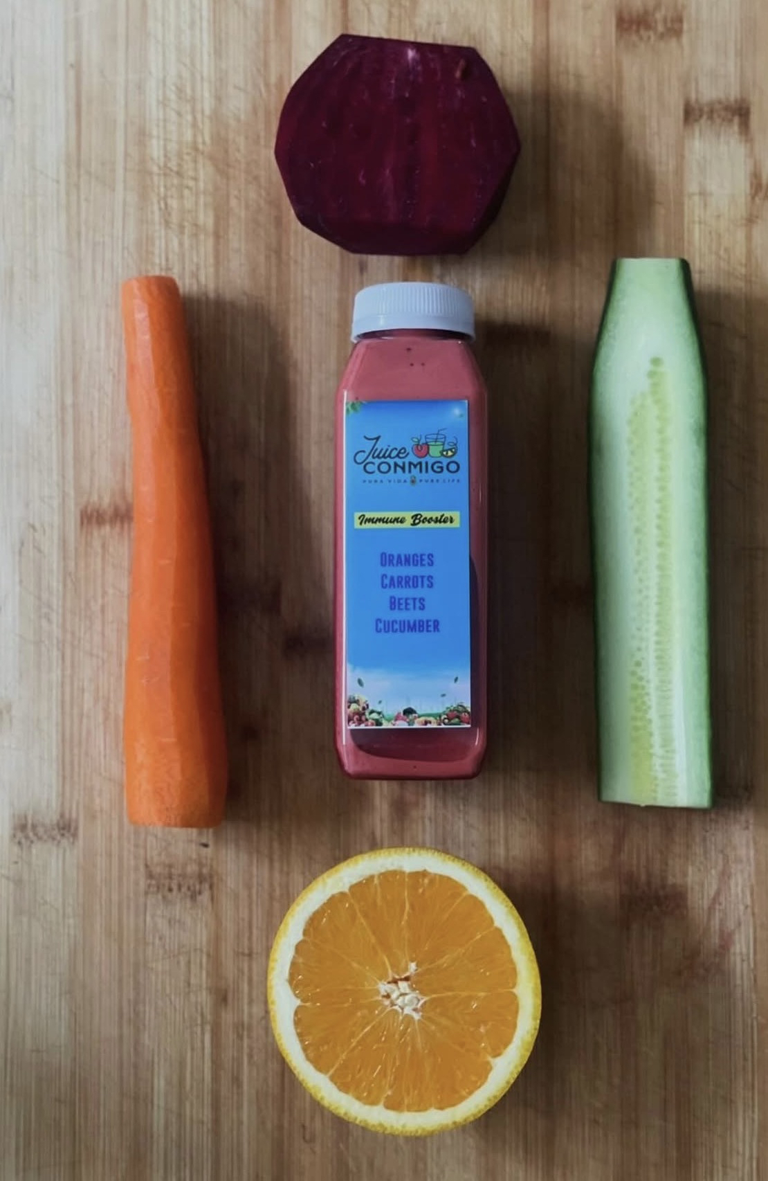 A bottle of Juice Conmigo's Immune Booster juice, with oranges, carrots, beets and cucumber.