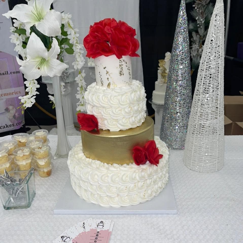 Cake de boda de Kat's Exquisite Cakes, con rosas rojas y acabado en dorado.
