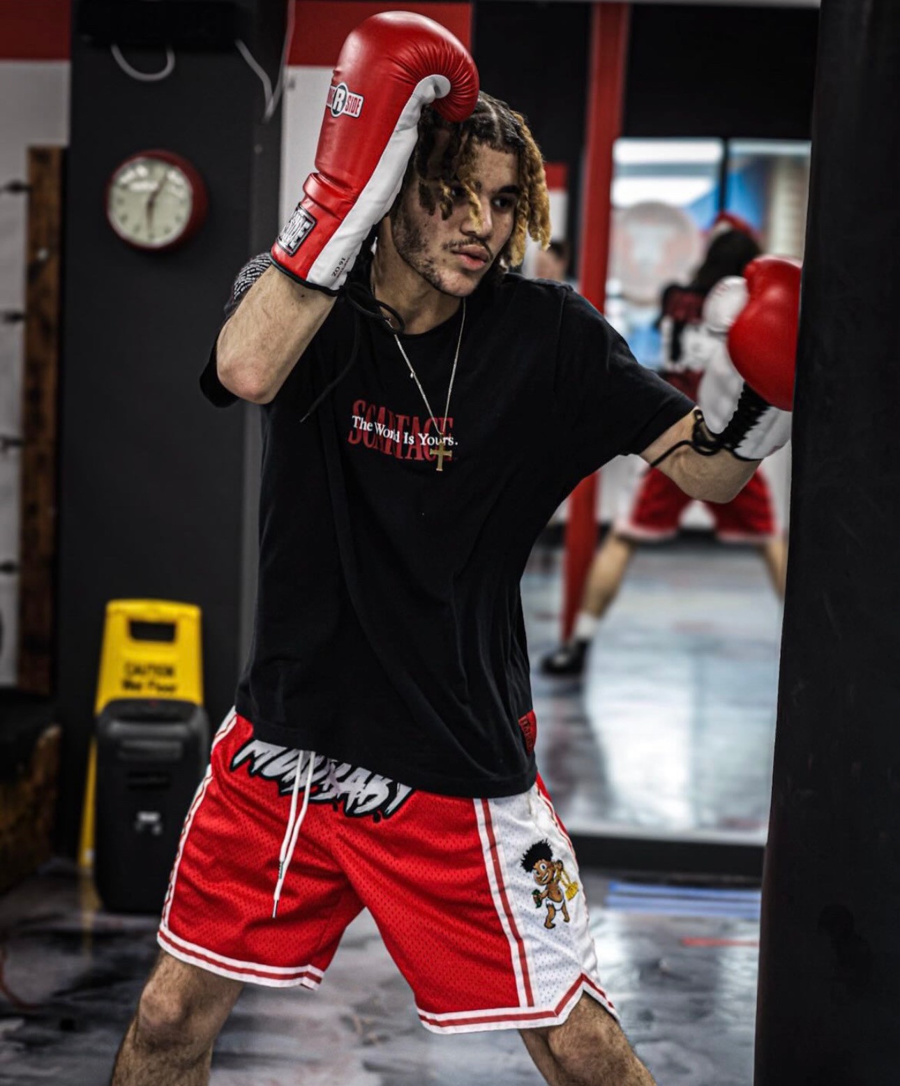 Shorts rojos y blancos de Mud Baby con el rótulo de la marca, fotografiados en un gimnasio de boxeo.