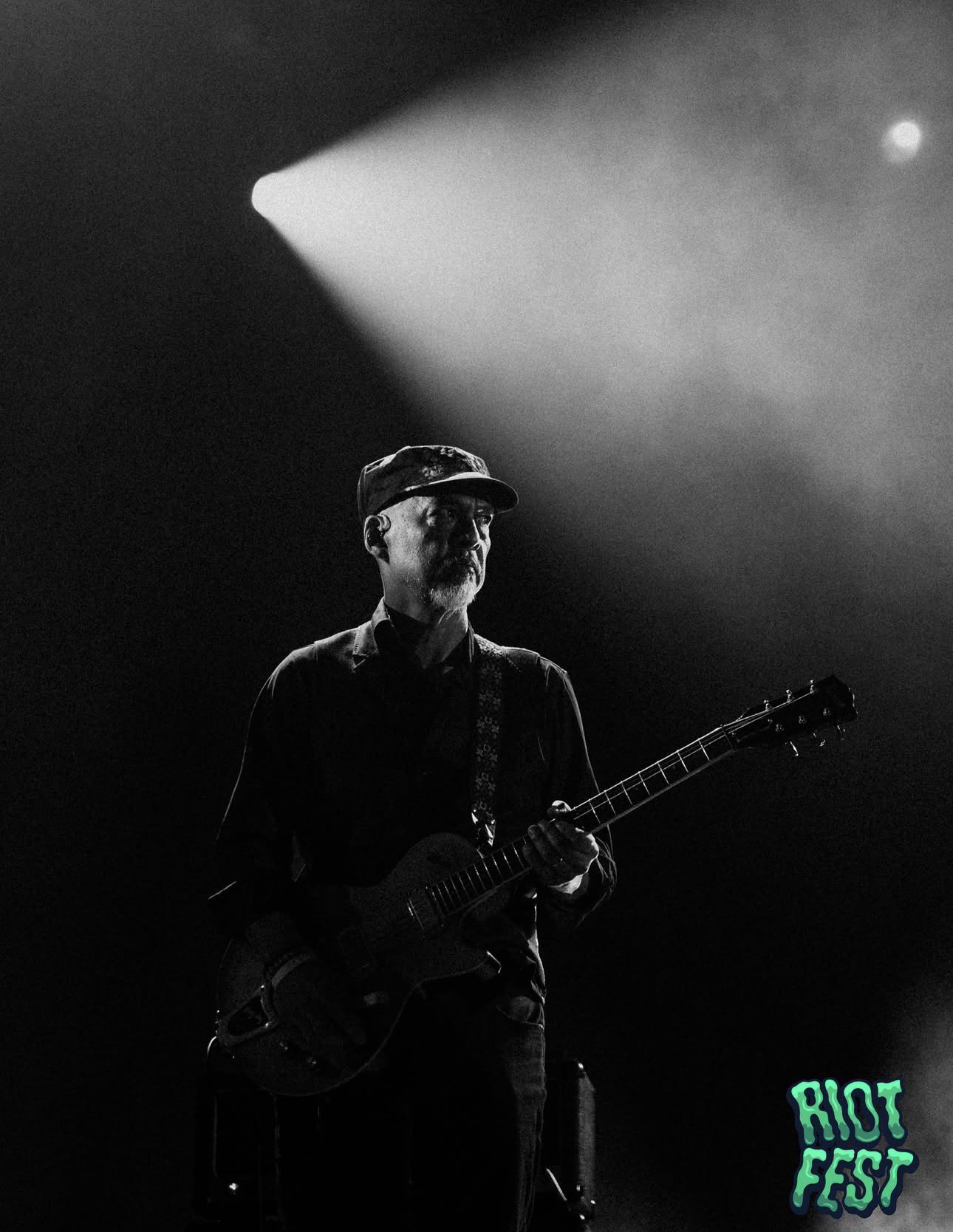 Guitarrista de Pixies en el escenario de Riot Fest, bajo un haz de luz