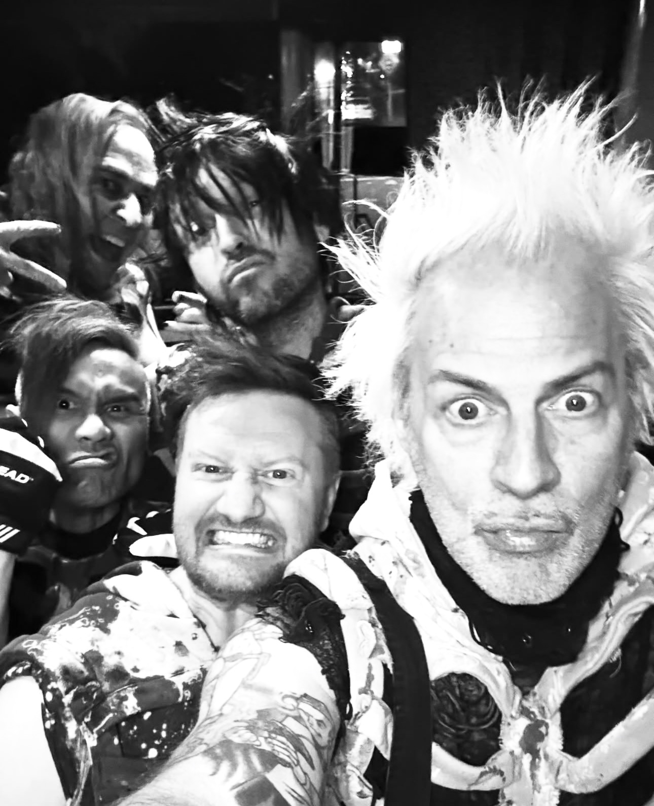 Selfie en blanco y negro de cinco hombres apiñados, con gestos exagerados
