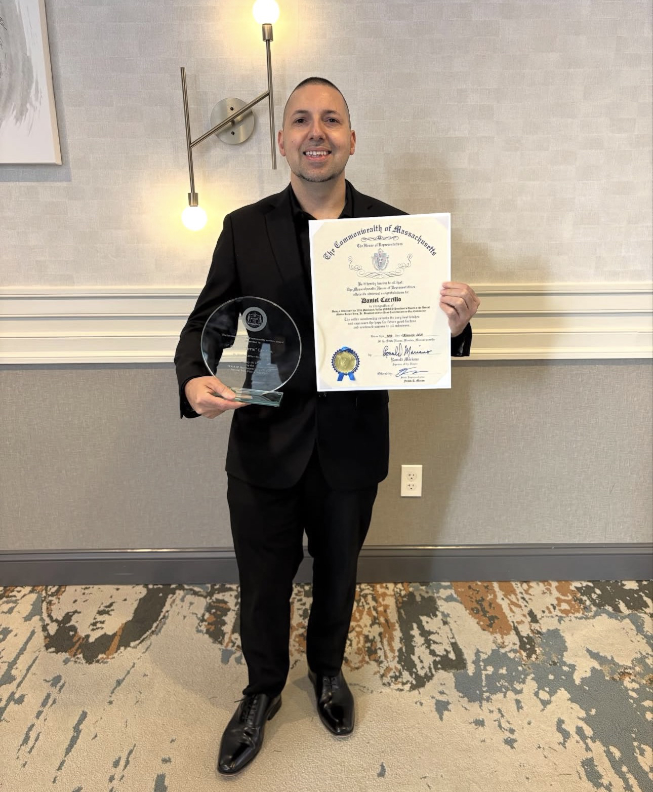 Termanology sosteniendo una citación de la Cámara de Representantes de Massachusetts y un premio de vidrio